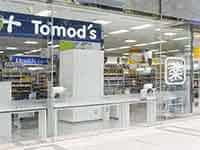 「Tomod's」のロゴと「薬」の表示が見えるドラッグストアの入口。