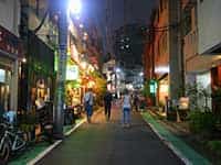 渋谷の喧騒から離れた裏渋谷通り。細い路地に人々が歩き、隠れた名店が並ぶ夜の風景。
