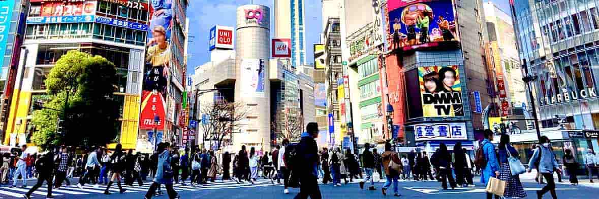 昼間の渋谷の賑わい。ファッションビルが立ち並び、活気ある人混みが通りを埋め尽くす。