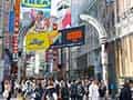 渋谷センター街のアーチが見える入口付近。多くの人が行き交い、巨大な看板が立ち並ぶ。