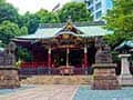 渋谷にある金王八幡宮の社殿。朱色の柱と緑の屋根が特徴的で、手前には狛犬が見える。
