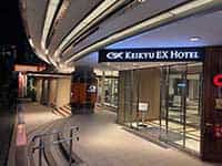 夜の京急EXホテル高輪の入り口。モダンなデザインの建物に「KEIKYU EX HOTEL」のロゴが明るく光っている。