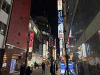 夜の品川駅東口の路地。左右のビルには多くの飲食店が軒を連ね、様々な看板が光っている。