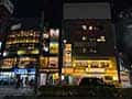 品川駅東側の飲食店街の夜景。複数のビルに居酒屋やレストランの看板が明るく灯る。