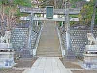 緑豊かな中に建つ品川神社の鳥居と社殿。参道は土で、日本の伝統的な風景を感じさせる。