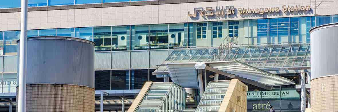 JR品川駅舎の外観。ガラス張りのモダンなデザインで、「JR品川駅 Shinagawa Station」の大きなロゴが見える。