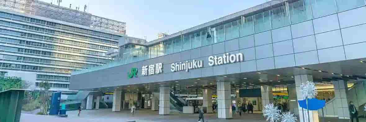 JR新宿駅の新南口。ガラス張りの近代的な駅舎と「JR新宿駅 Shinjuku Station」の大きな看板が見える。