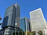 青空を背景にそびえる丸の内の高層ビル群。商業施設やオフィスが一体となった都市空間。