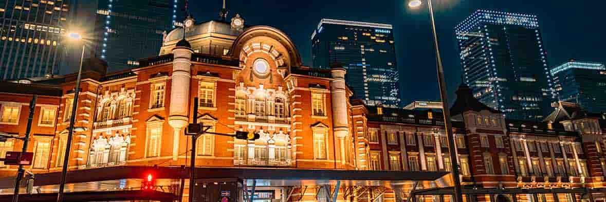 美しく照らされた東京駅丸の内駅舎の夜景。駅の機能だけでなく、宿泊施設としての役割も果たすこの歴史的建造物が、都会の夜に静かに佇む。
