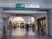 「JR上野駅 Ueno Station」の案内板と、駅構内の賑わい。
