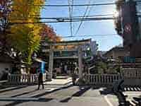 都会の街並みに溶け込む下谷神社の鳥居と、参道を歩く人々の姿。